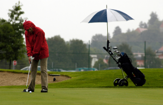 雨の日のゴルフをプレーする男性